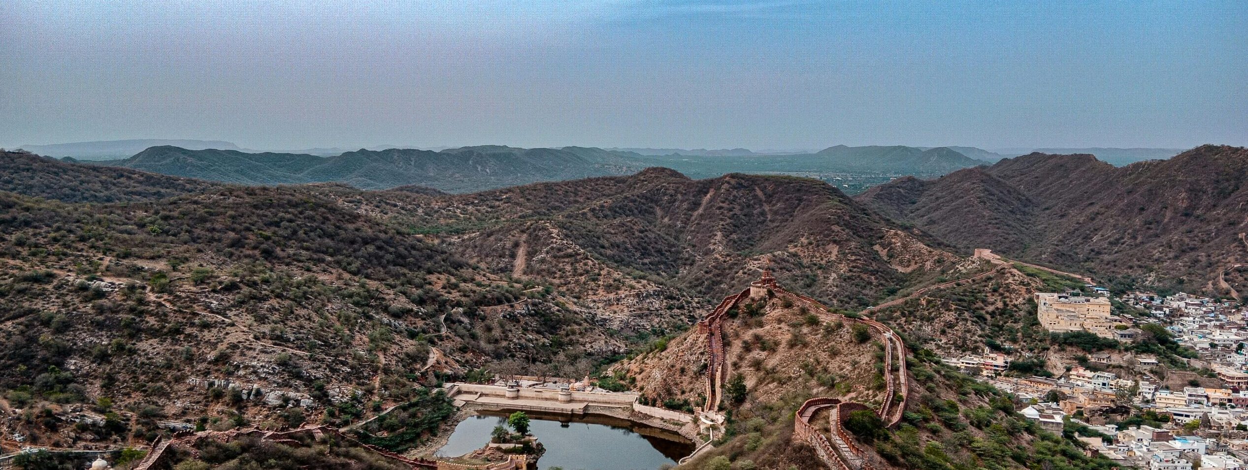 Stunning aerial view capturing Amer Fort and rolling hills in Jaipur, Rajasthan, showcasing historic architecture and natural beauty.