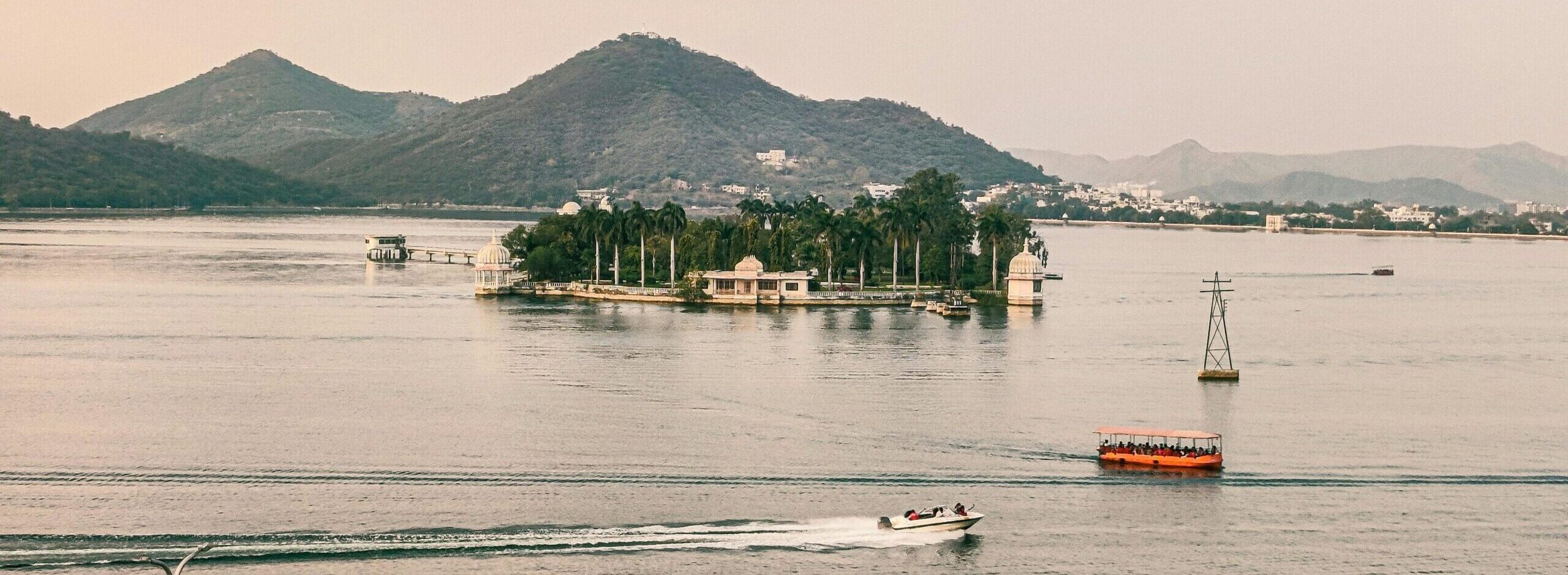 A serene aerial view of Lake Pichola with boats and hills in Udaipur, India.